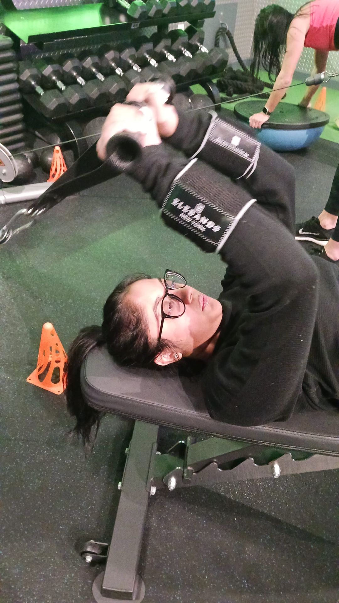 Woman strength training with EleBands wrist weights in a gym