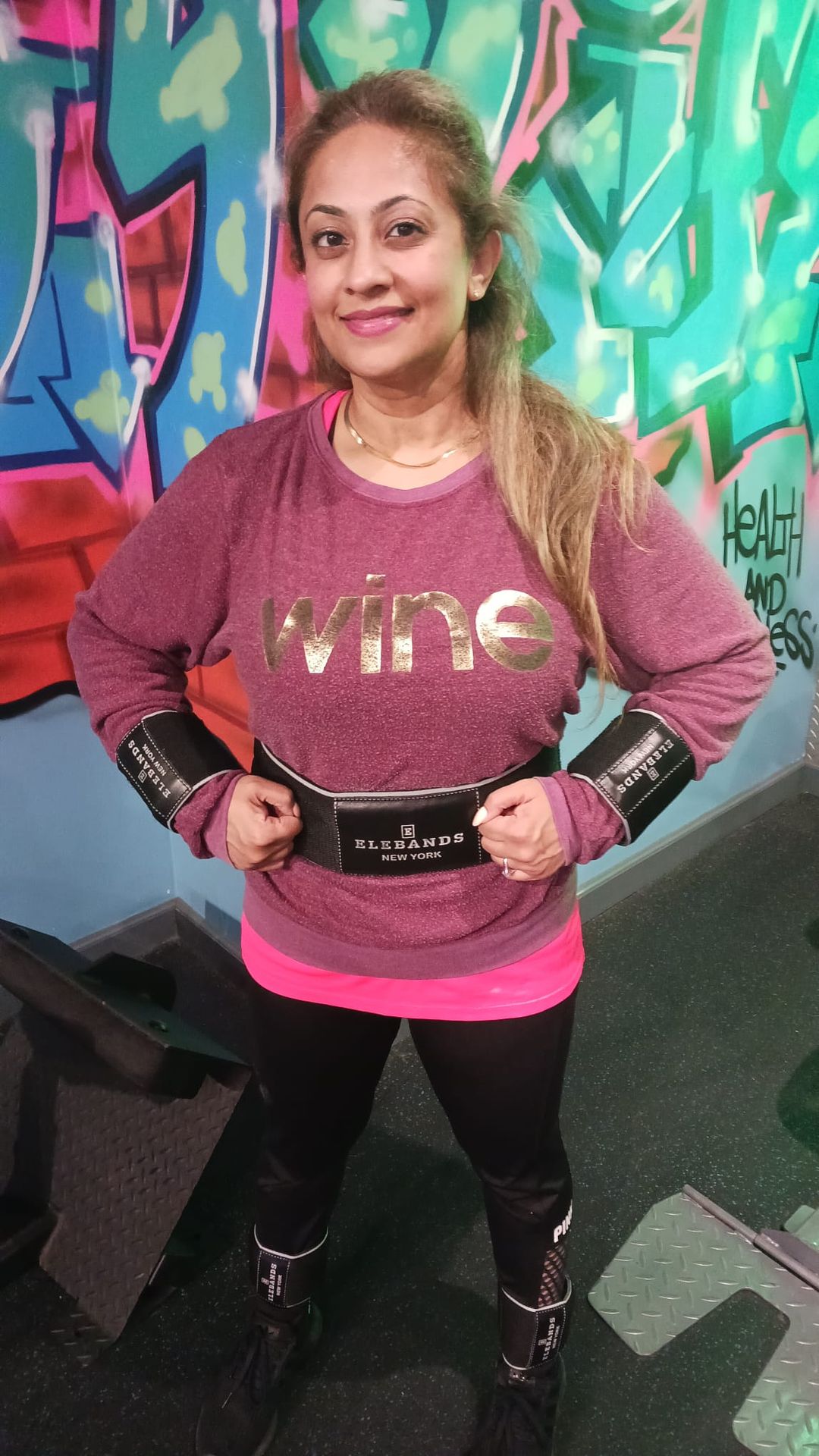 Woman demonstrating an EleBands waist weight at a gym