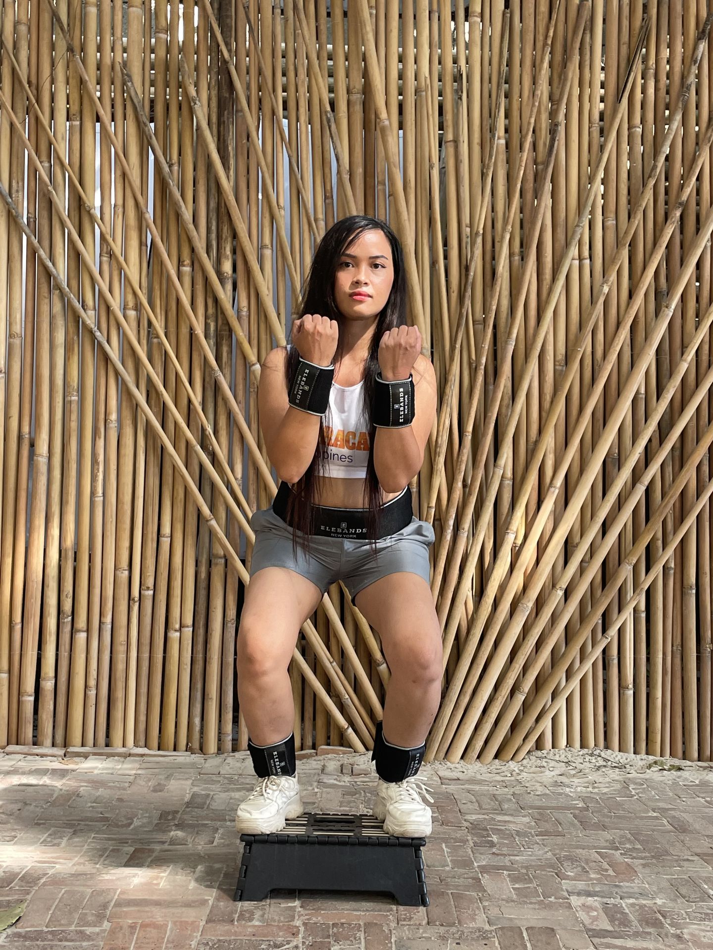 Woman doing a squat exercise with EleBands wrist and ankle weights
