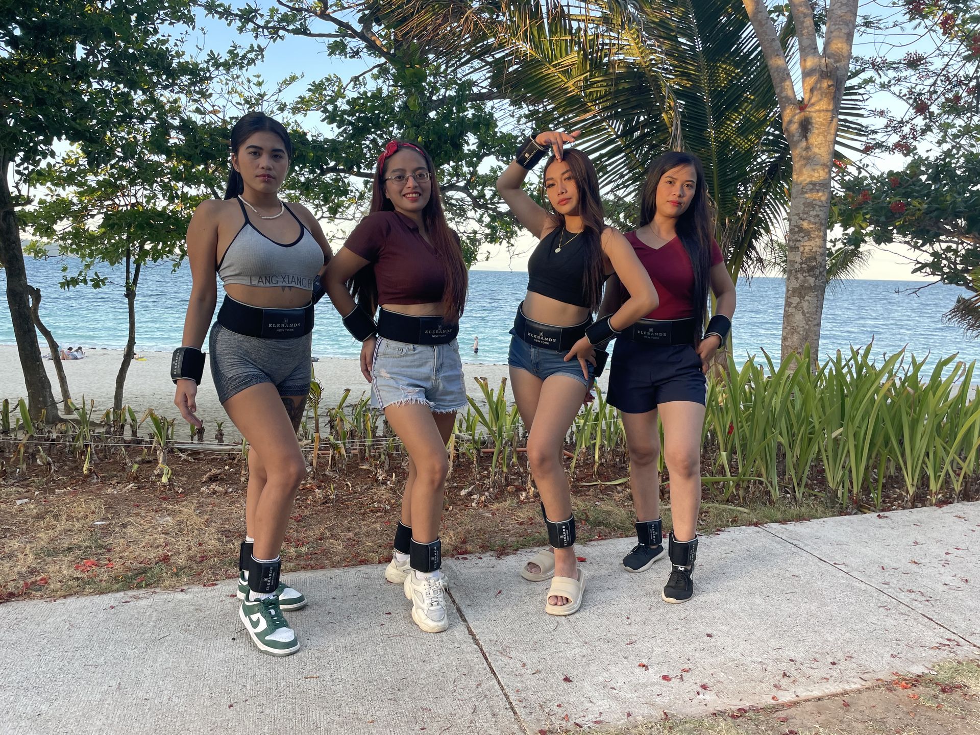 Four women walking outdoors with EleBands fitness weights